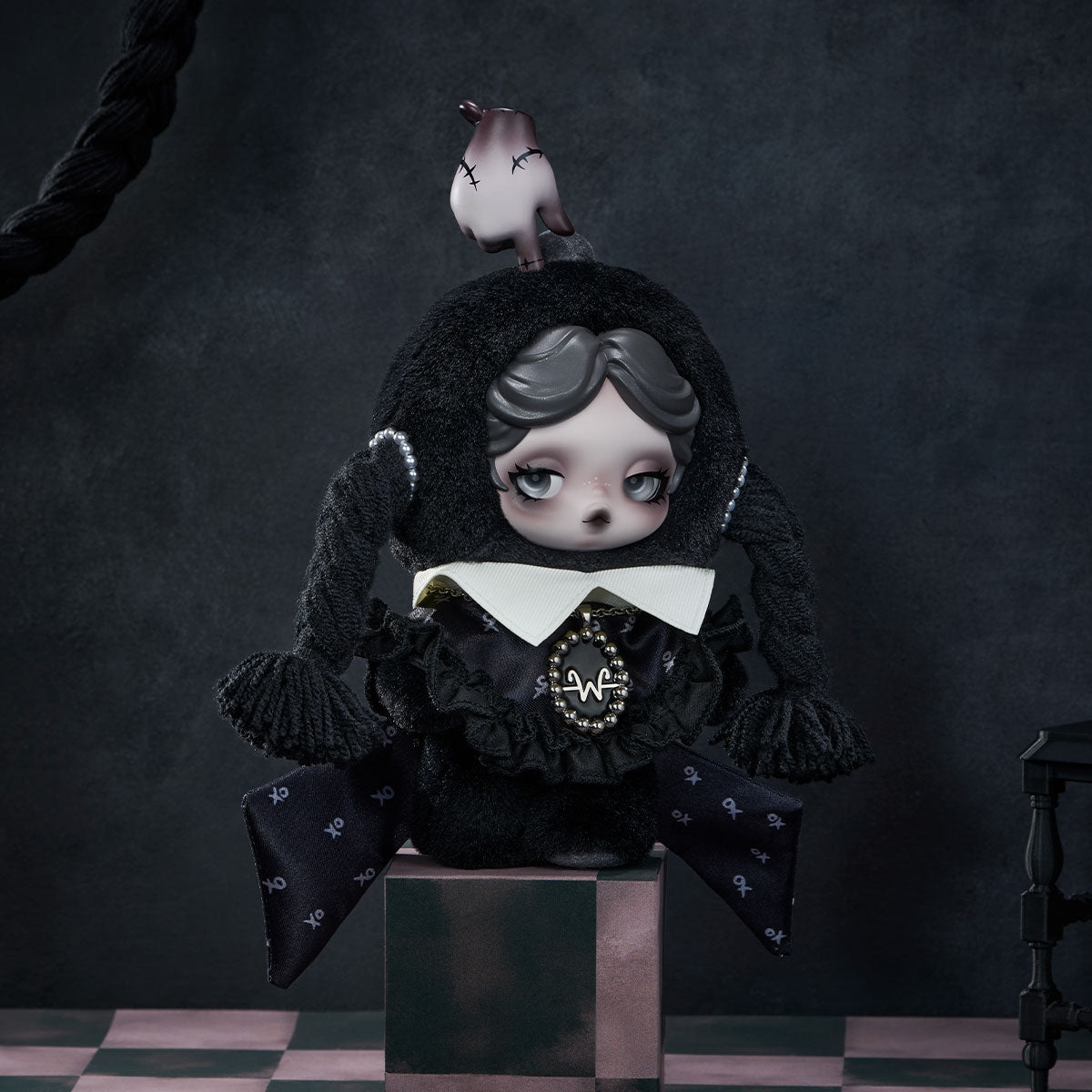Classic Dress plush frontal pose with dark skull-pattern dress, white collar, braids and sculpted hand-on-head detail; pedestal is display styling