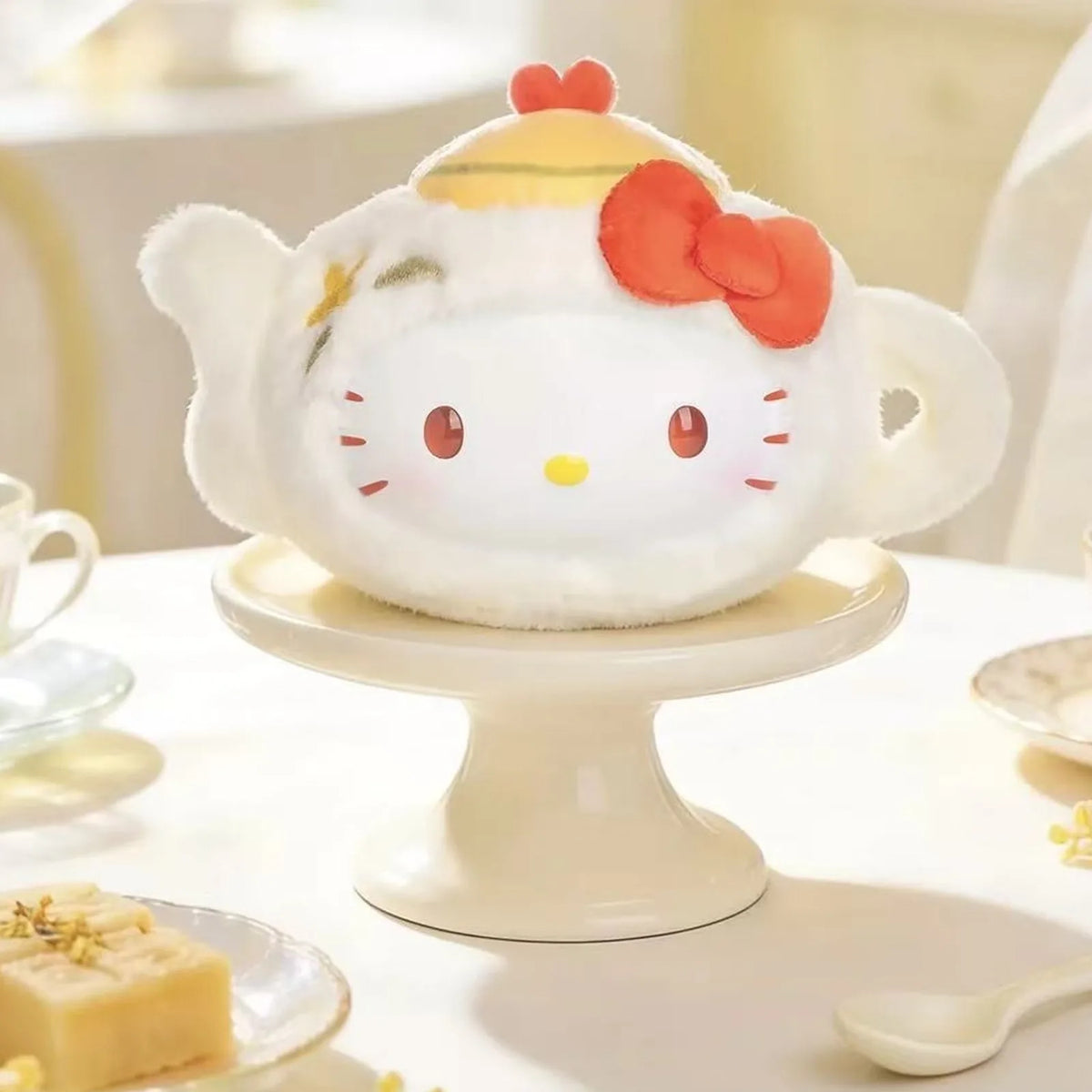 Yellow teapot-shaped plush design example on a cake stand; display props are not promised as included