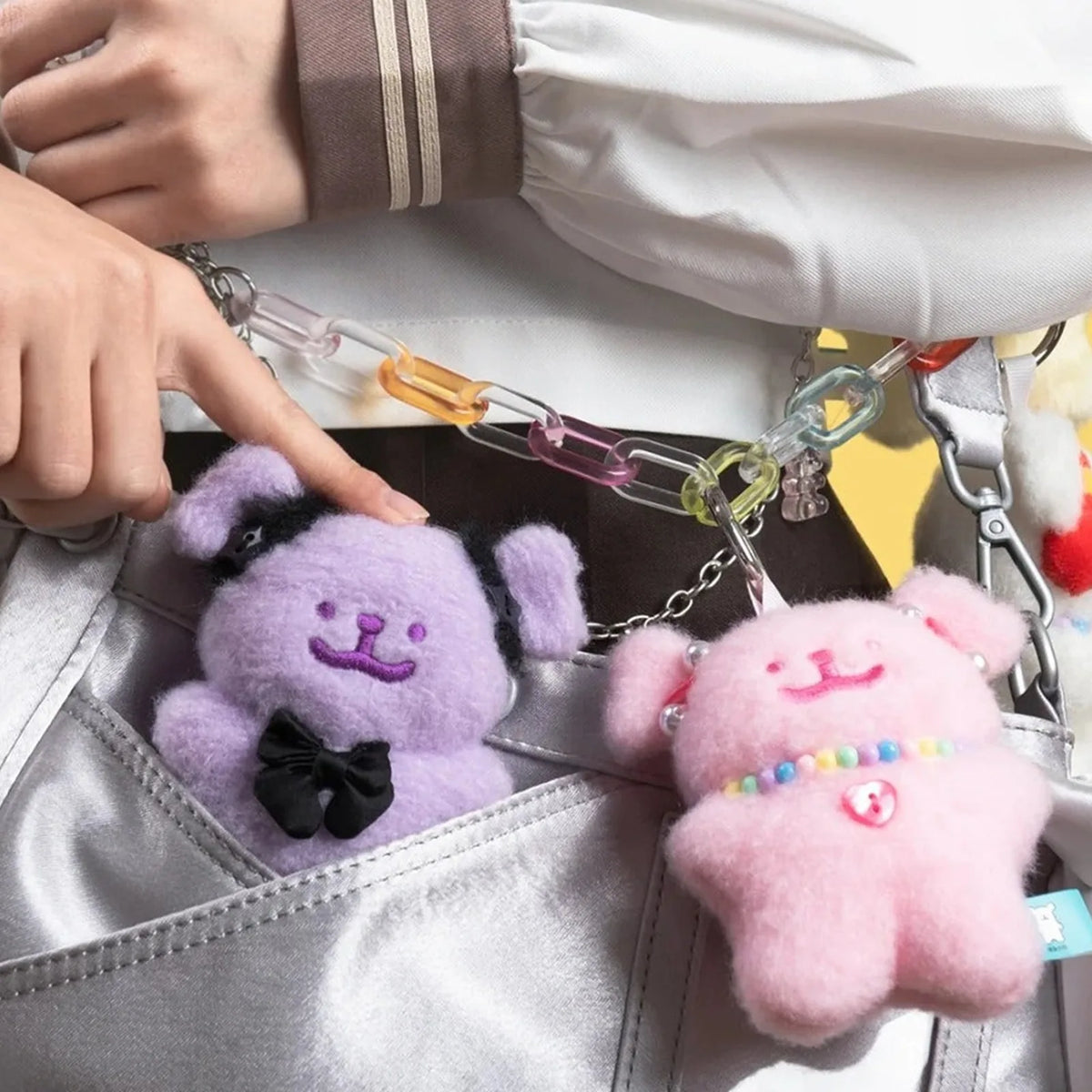Purple and pink Maltese Gummies plush pendants styled on a bag | KikiBuddies
