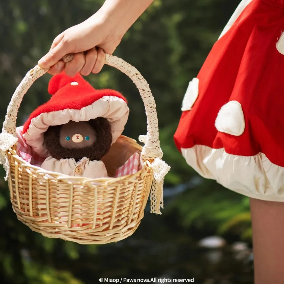 KUMARU Fairy Tale Town brown plush in a red mushroom hat, photographed in a basket; illustrative series design