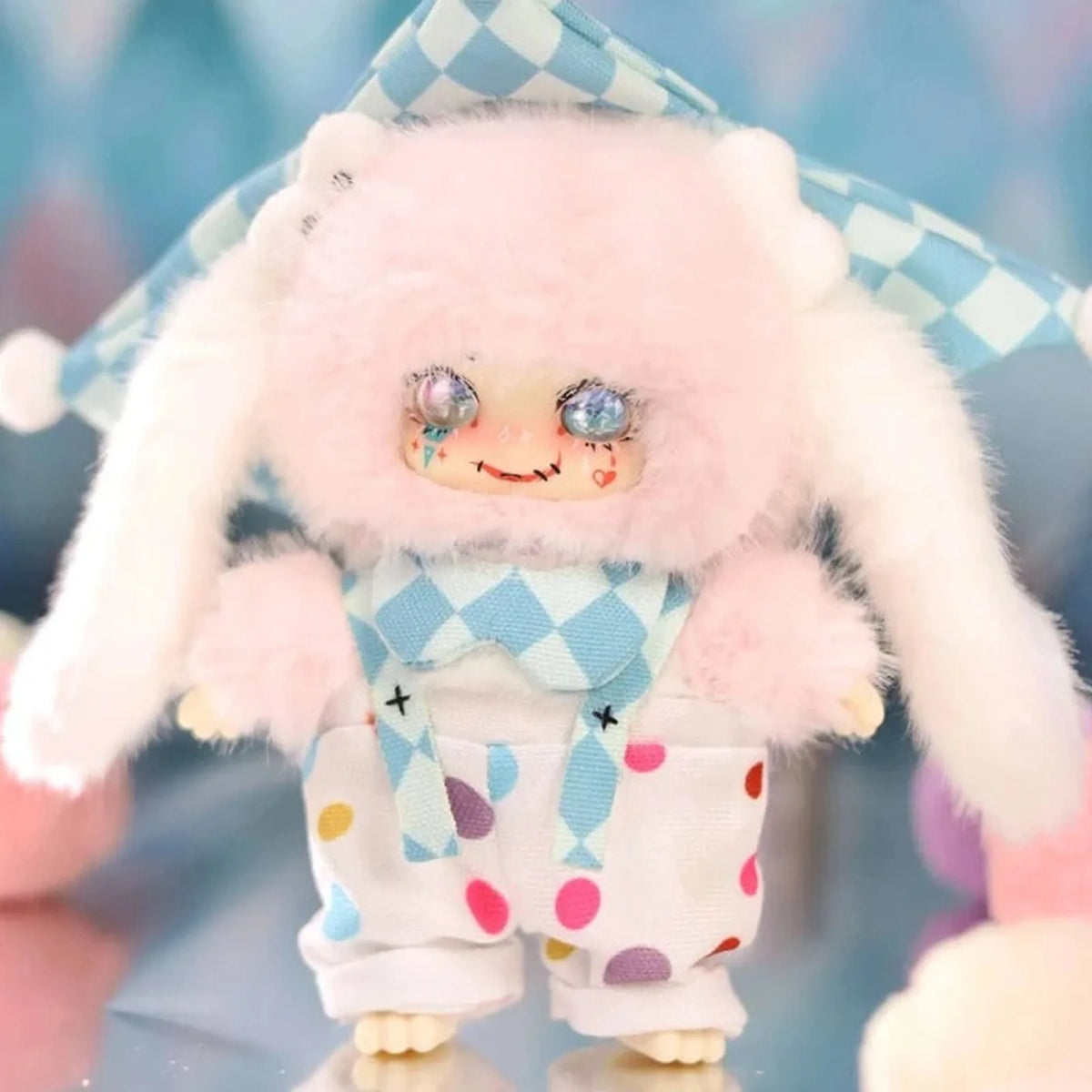 Pink LOKIKI plush in a diamond-pattern jester costume; series design example | KikiBuddies