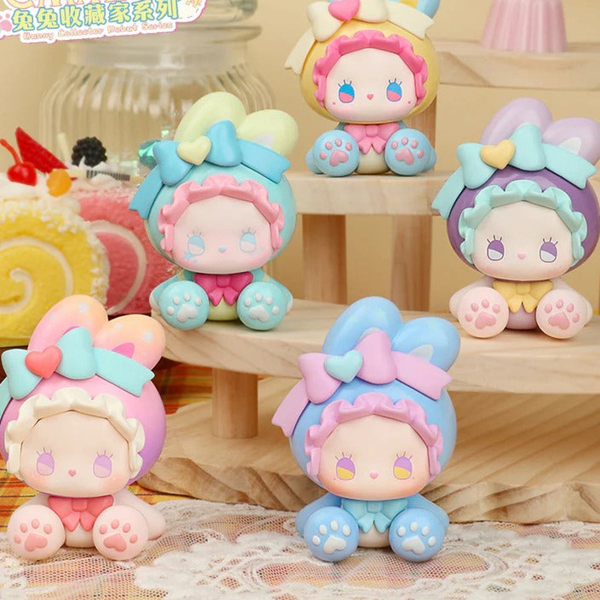 EMMA Bunny Collector Debut five pastel rabbit-hood figure designs with bows and paw-pad details; design reference only