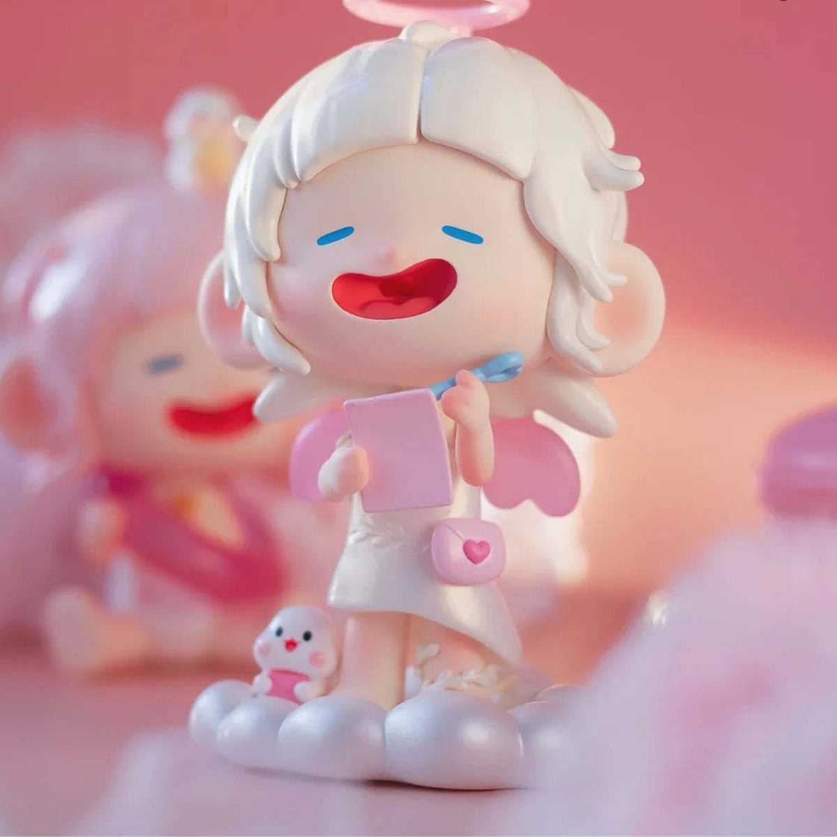 Pink Dream angel-style figure with book and cloud details; photographed design example, not guaranteed