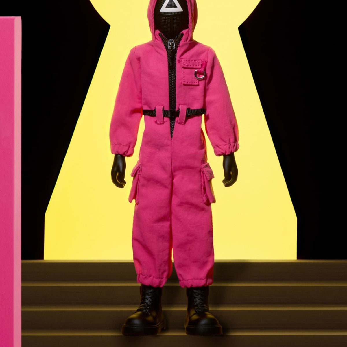 Squid Game masked action figure in a pink suit, shown in a display scene