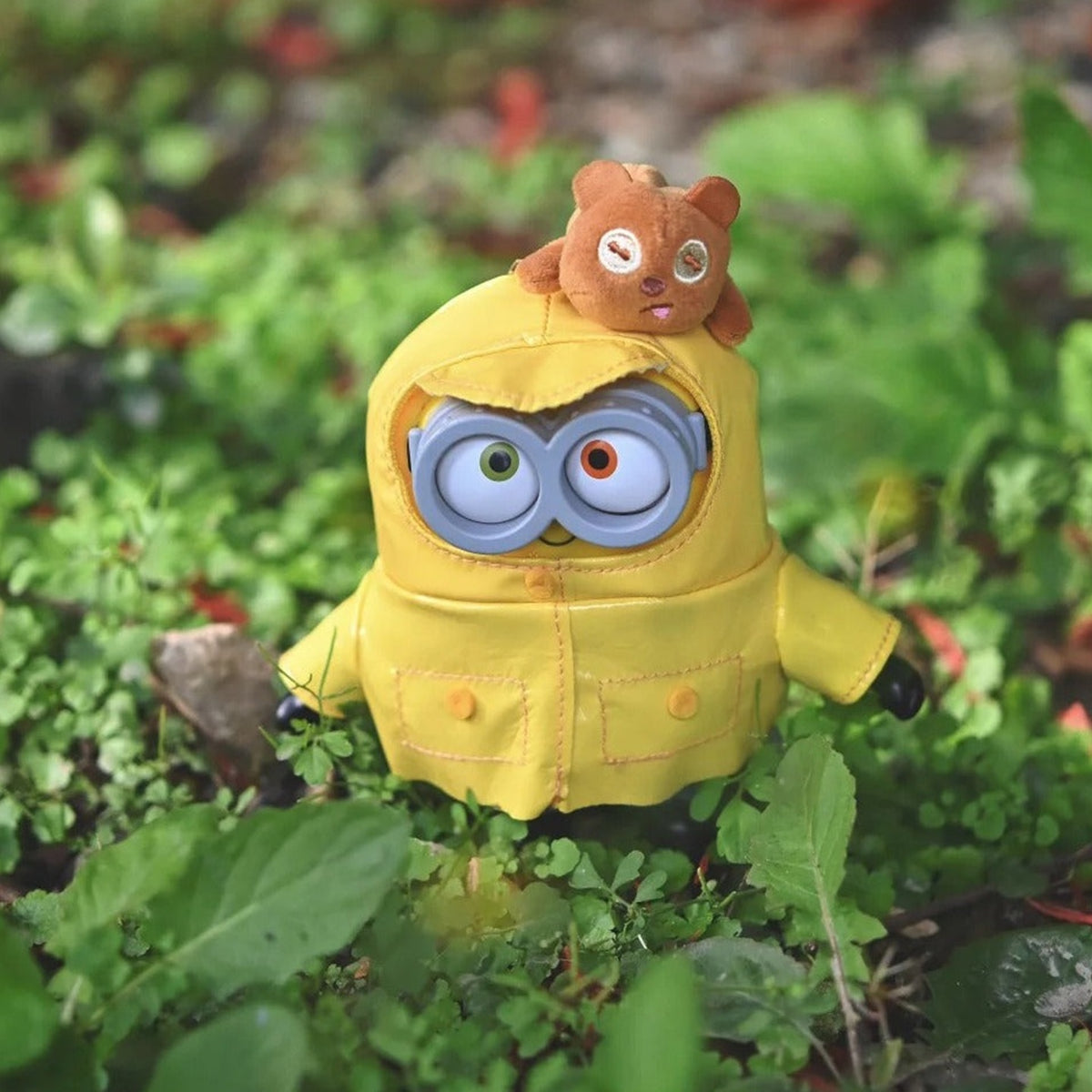 Minions Bob and Tim Best Buddies Forever Series Vinyl Plush Keychain Blind Box - Yellow raincoat vinyl plush keychain with top bear detail and lower boots partly obscured by grass; random design not guaranteed