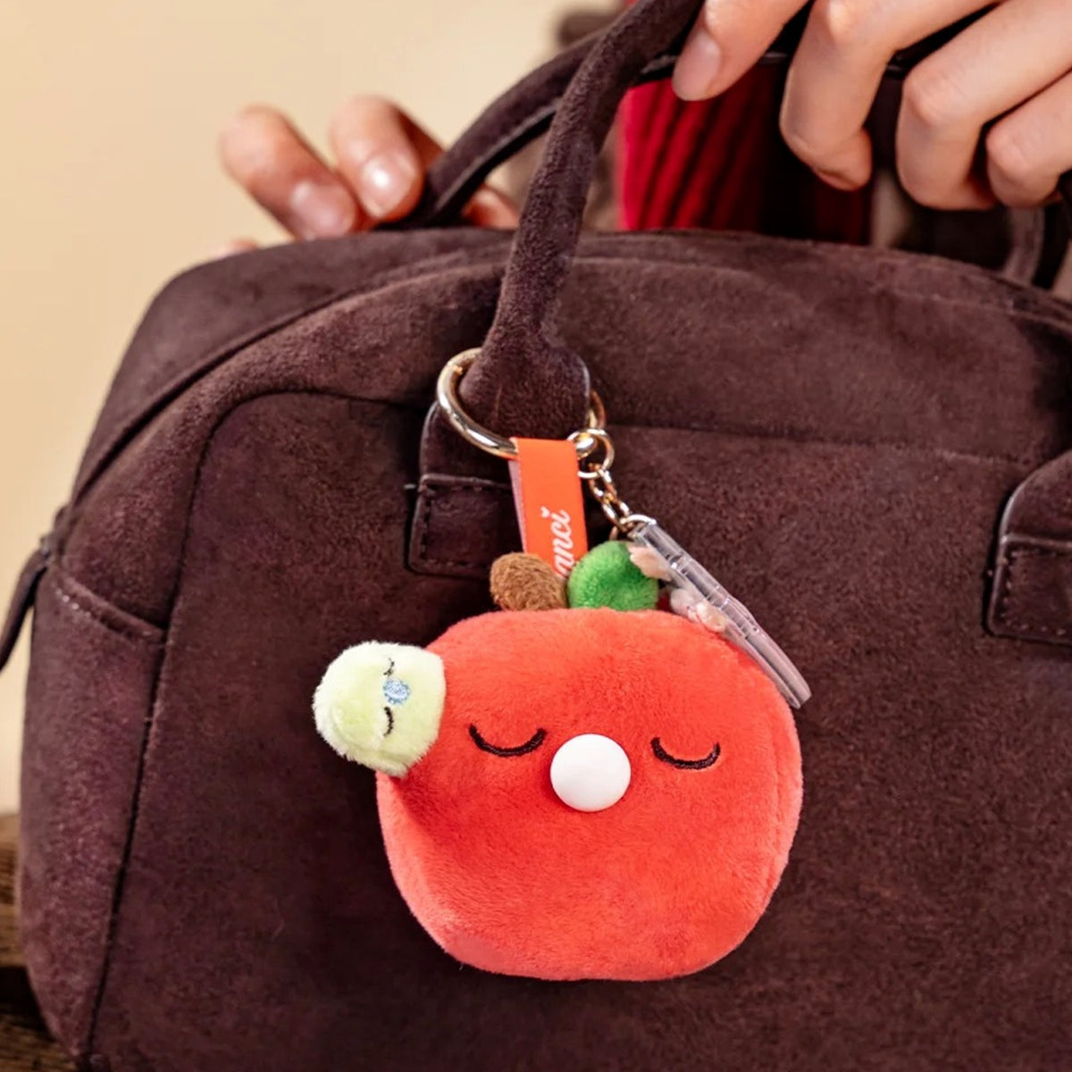 Nanci Good Luck Comes Around: Good Luck Comes Around red plush pendant attached to a bag; bag is a display prop
