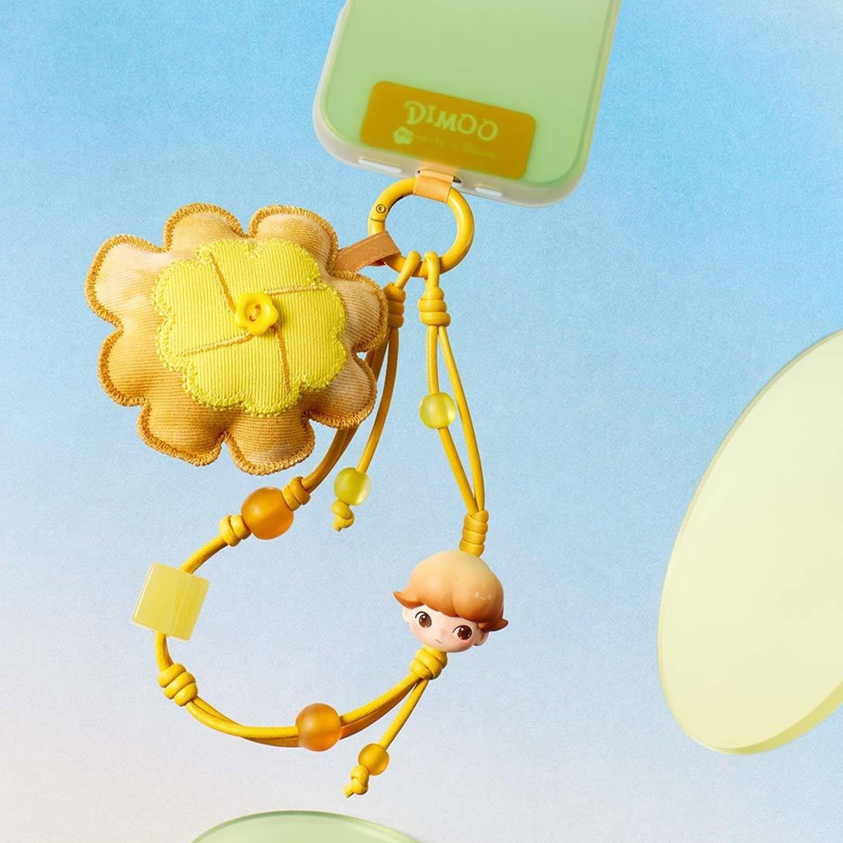 Yellow flower DIMOO Moments in Bloom decorative charm styled on a phone; the phone is a display prop.